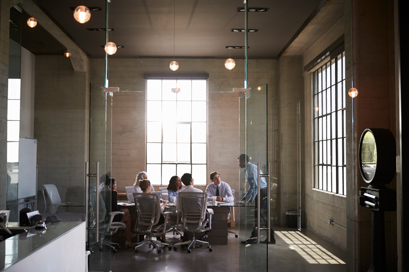 Business colleagues in a meeting in a glass walled boardroom, which does not provide adequate speech privacy for meeting spaces according to acoustic consultants