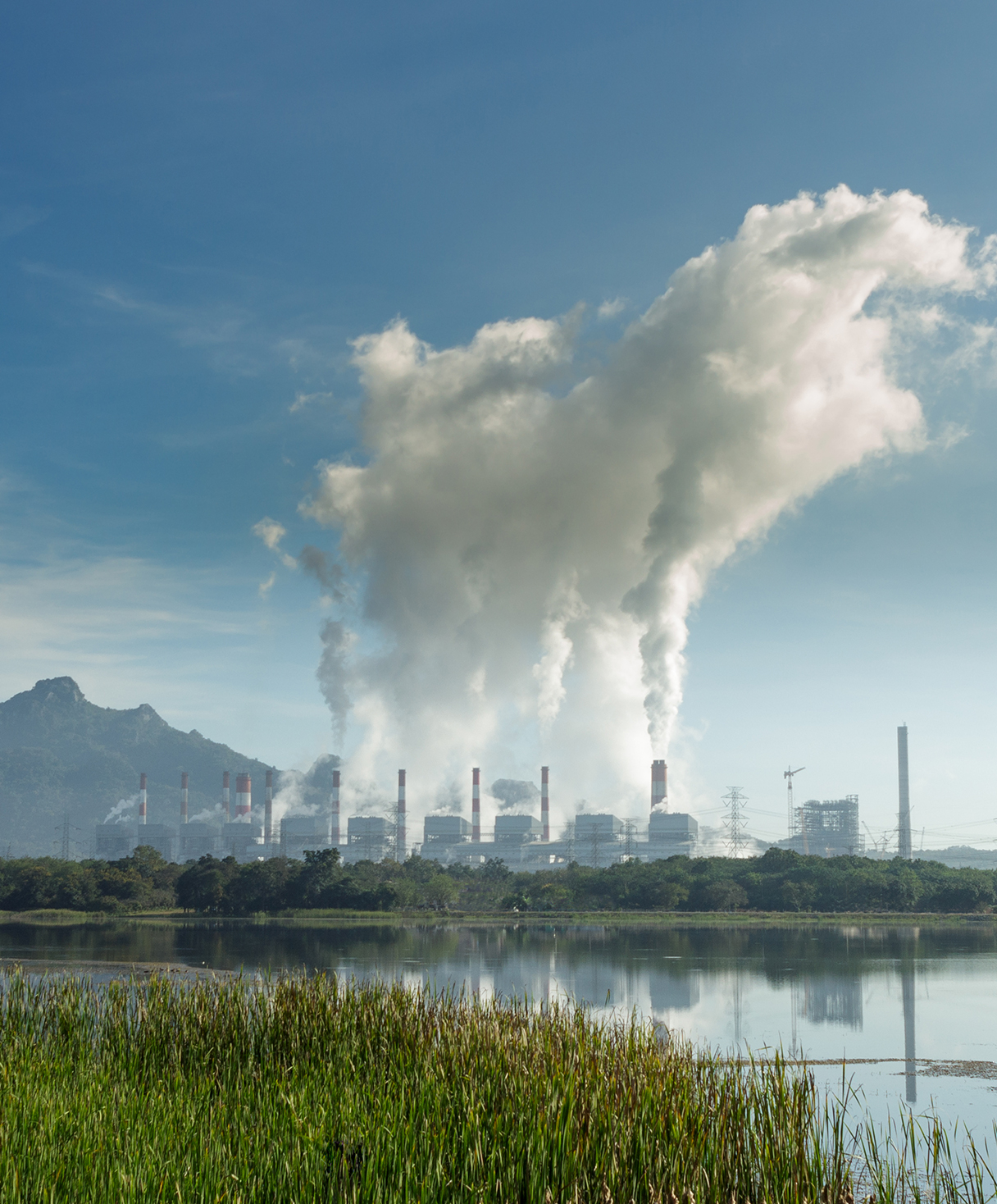 Hot steam from chimney at coal power plants against blue sky.