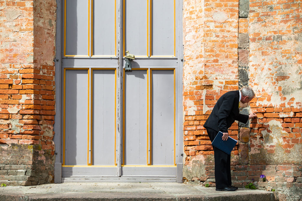 man inspecting brick wall