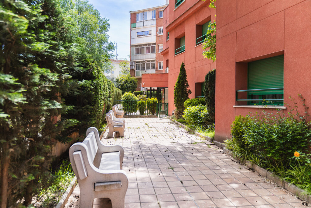 Comfortable benches provide a peaceful resting spot amidst lush greenery in the garden of a nursing home.